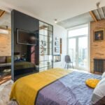 Stylish contemporary bedroom with yellow bedspread and brick walls.